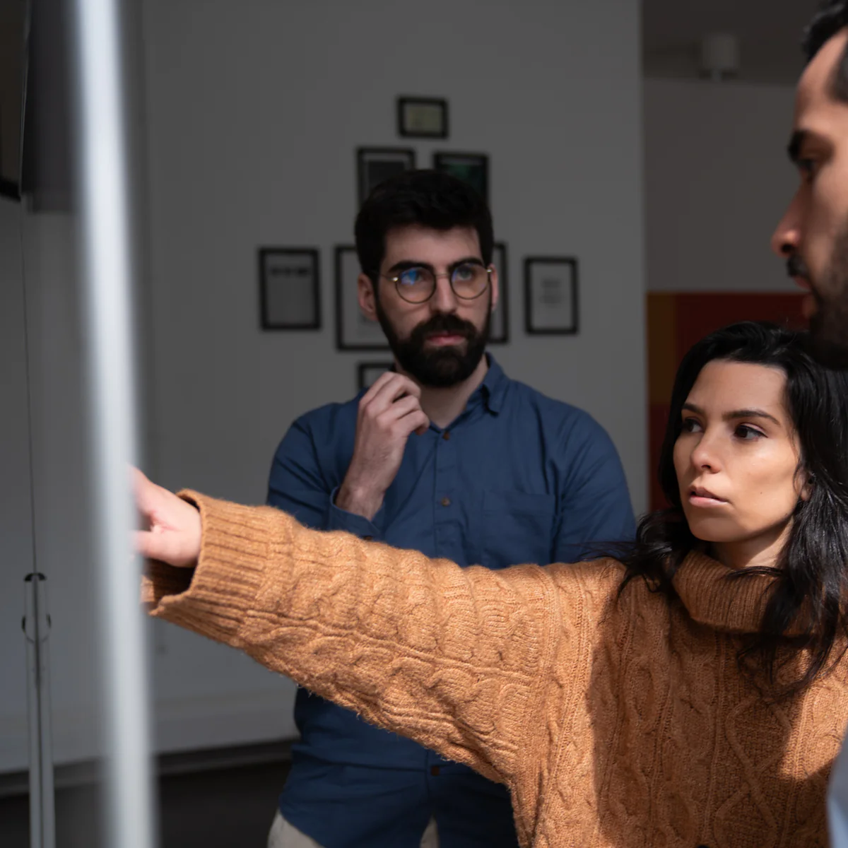 An AppX team member explaining something at the board while two colleagues listen