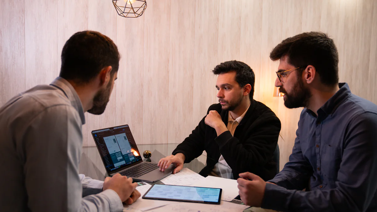 Three of the AppX team around a laptop and a tablet in a working session