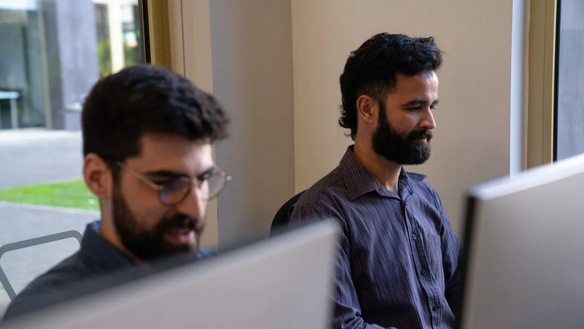 Two AppX developers at their screens in the open office